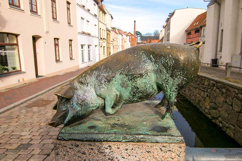 Eine Bronze in Wismar: Auf der Schweinsbrücke räkeln sich Schweine.