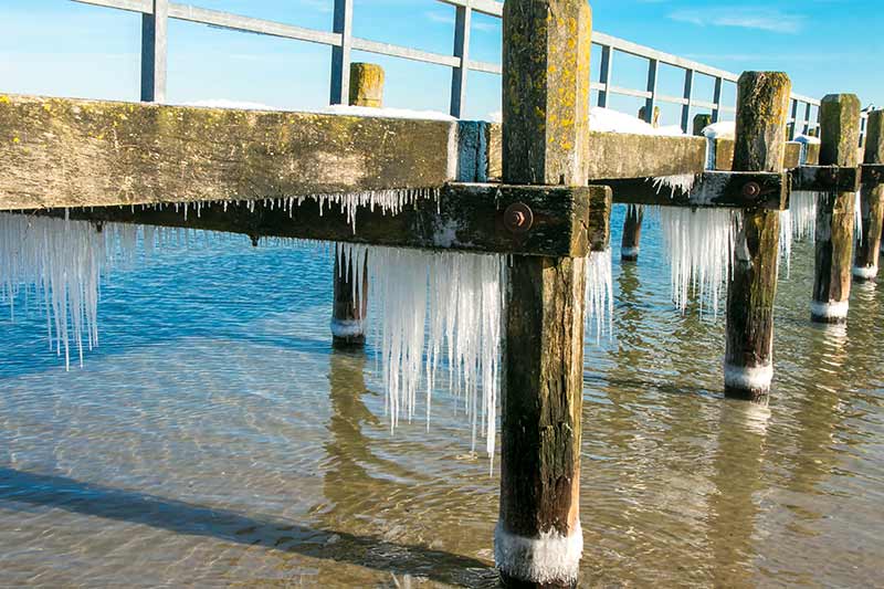 Eiszapfen unter einem alten Steg in Travemünde