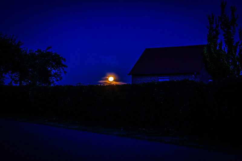 Der Erdbeermond hinter dem Häusern in unserem Dorf.