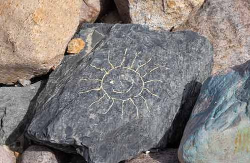 Sonnenstein - mit einer Sonne bemalter Stein an der Steilküste.
