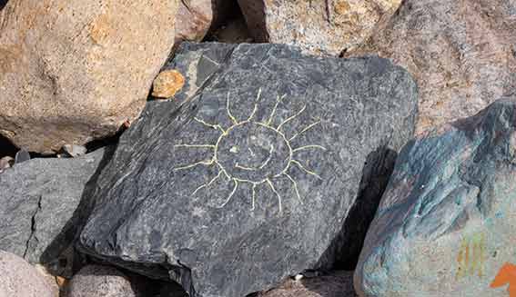 Sonnenstein - mit einer Sonne bemalter Stein an der Steilküste.