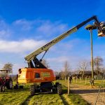 Ein Hubsteiger hievt ein Storchennest auf einen Pfahl.